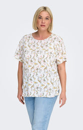 Woman wearing a white blouse, with a floral design all over and light blue jeans on a white background