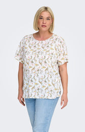 Woman wearing a white blouse, with a floral design all over and light blue jeans on a white background