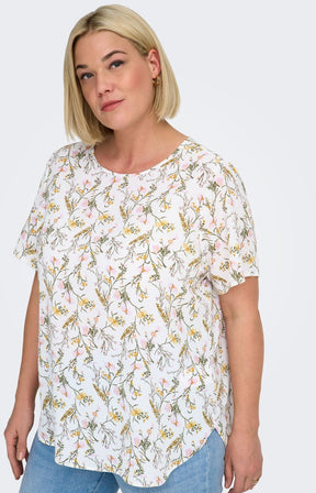 Woman wearing a white blouse, with a floral design all over and light blue jeans on a white background