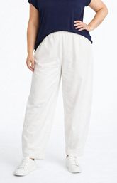 Person wearing a navy top and white pants on a white background