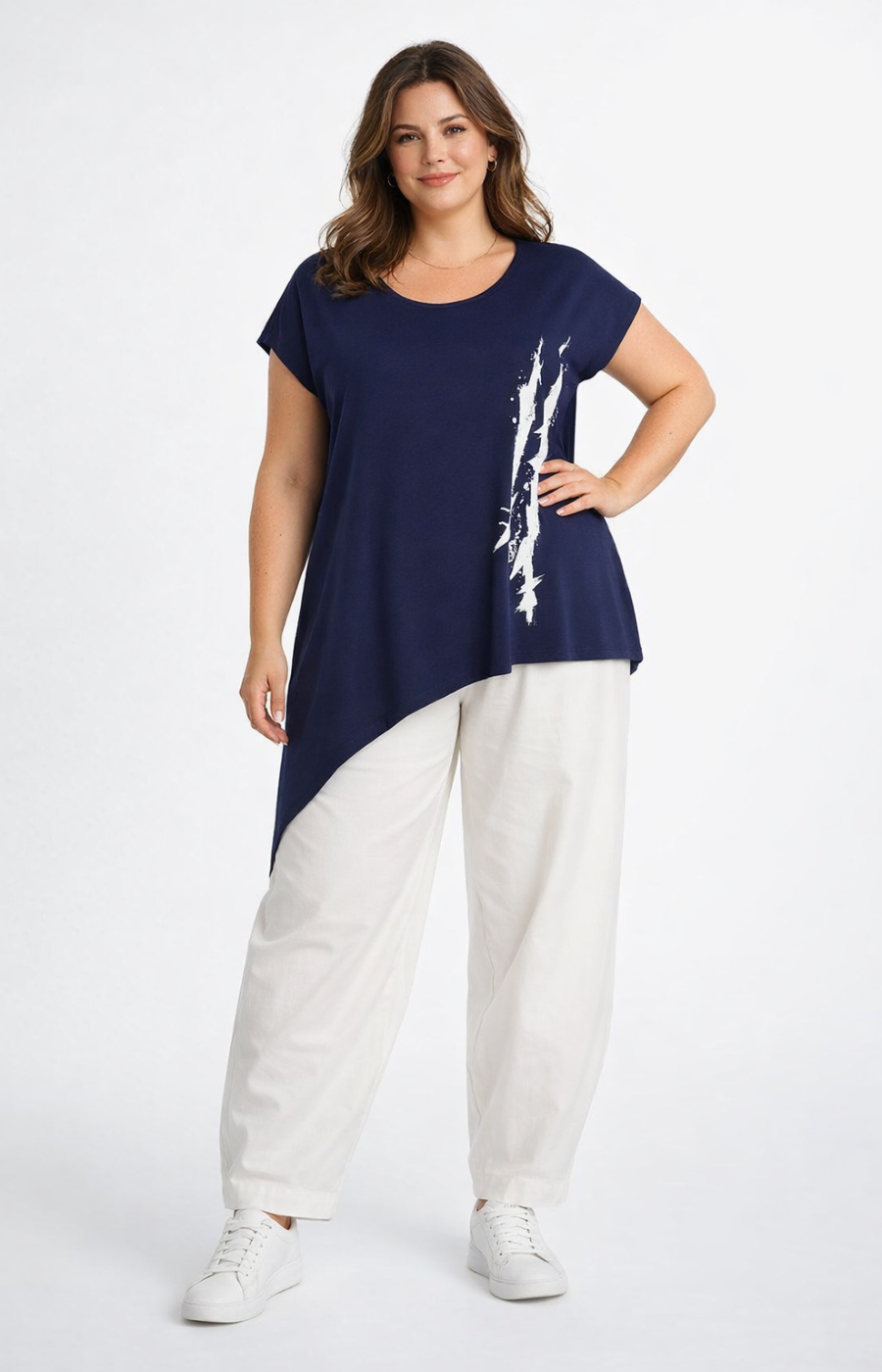 Woman wearing a navy top with a white graphic and white pants on a white background
