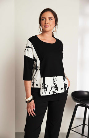Woman wearing the Ora Contrasting Hem Top in Black, a black top with a contrasting side and hem with a round neckline, 1/2 length sleeves, cut out on the hem, pocket on the front with a plain background 