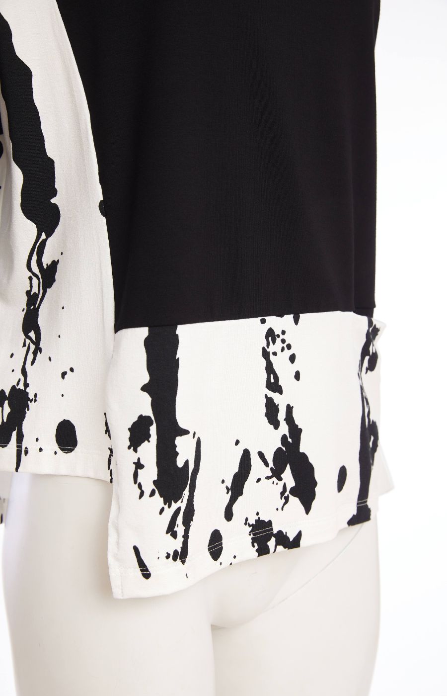 Woman wearing the Ora Contrasting Hem Top in Black, a black top with a contrasting side and hem with a round neckline, 1/2 length sleeves, cut out on the hem, pocket on the front with a plain background   