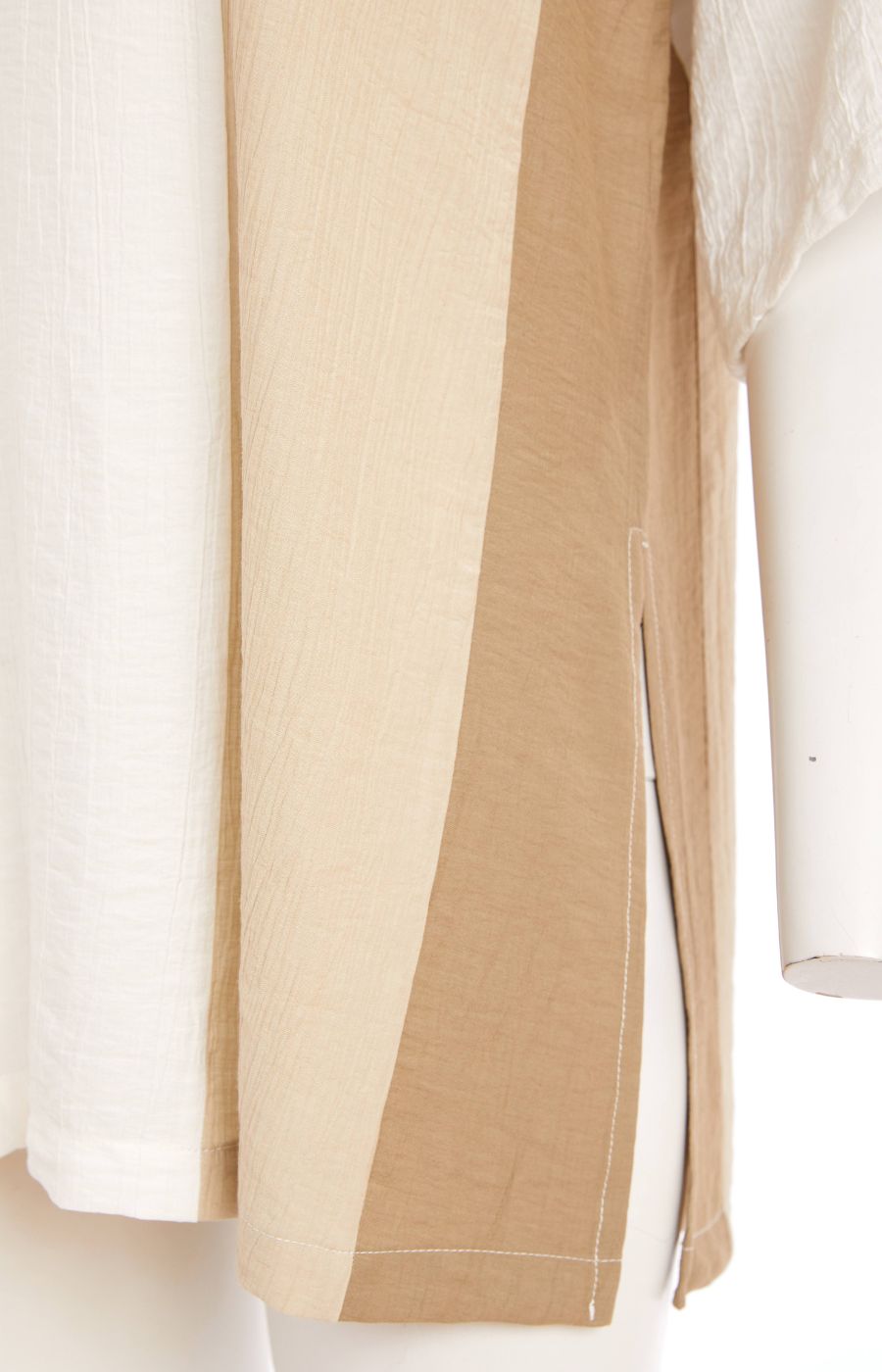 Woman wearing the Ora Crinkle Top with Collar in Beige, a white top with a beige side stripe down the front and back, a collard V neckline, short sleeves and side slits, worn with beige pants against a plain background   