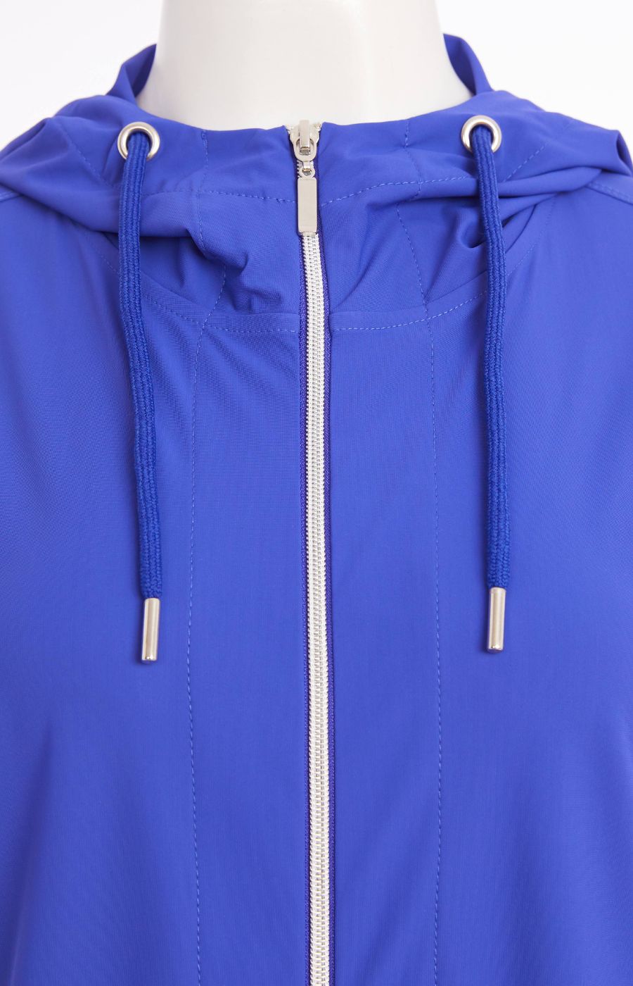 Woman wearing the Ora Hooded Jacket in Blue, with the blue Ora travel trousers a blue outfit with a white background  