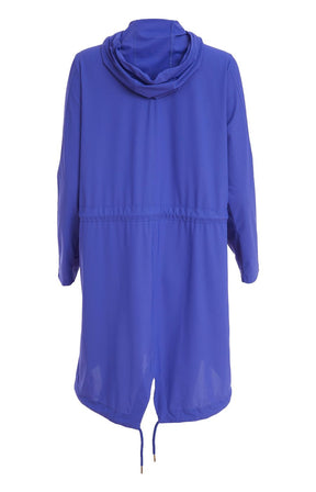 Woman wearing the Ora Hooded Jacket in Blue, with the blue Ora travel trousers a blue outfit with a white background  