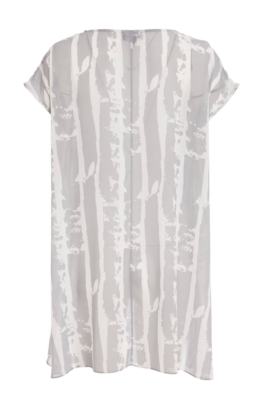 Woman wearing the Ora Layered Top in Grey, a slightly sheer, double layered top with a  light grey and white patterned top. Has a round neckline, short sleeves and a curved hem worn with white trousers against a plain background    