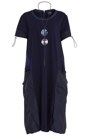 Woman wearing the Ora Side Pocket Dress in Navy, a navy blue dress with side pockets, round neckline and short sleeves, in a midi length.    
