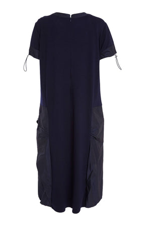 Woman wearing the Ora Side Pocket Dress in Navy, a navy blue dress with side pockets, round neckline and short sleeves, in a midi length.    
