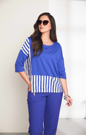 Woman wearing the Ora Striped Pocket Top in Blue, a blue top a round neckline and 3/4 length sleeves with white striped hem against a plain background  