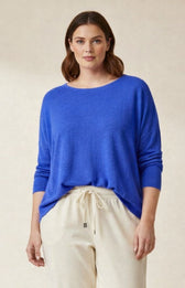Woman wearing a blue knitted sweater and beige pants on a plain background