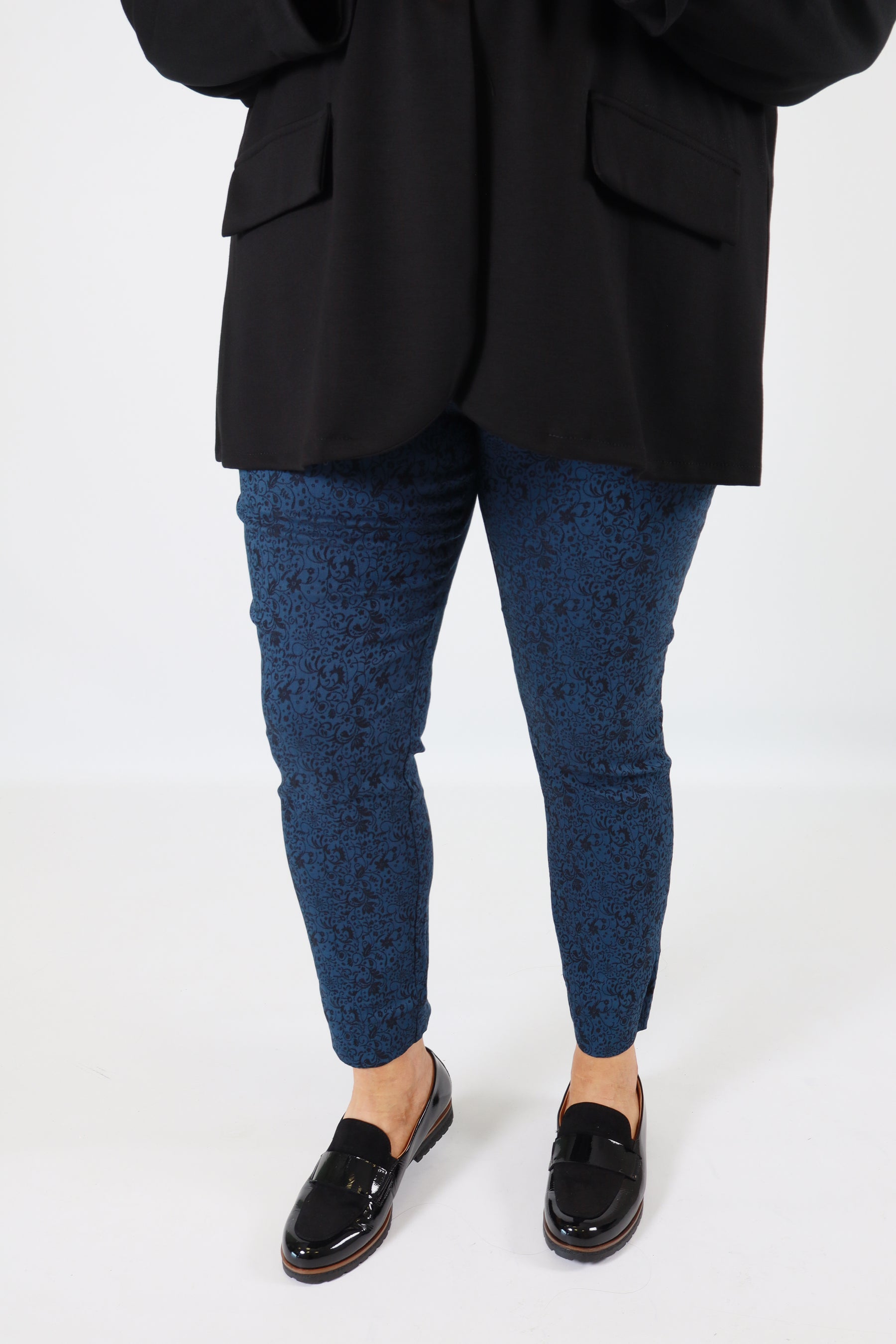 Person wearing black shoes, blue socks, and black pants on a white background