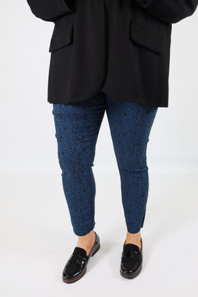 Person wearing black shoes, blue socks, and black pants on a white background