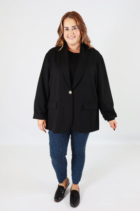 Person wearing a black blazer and blue jeans on a white background