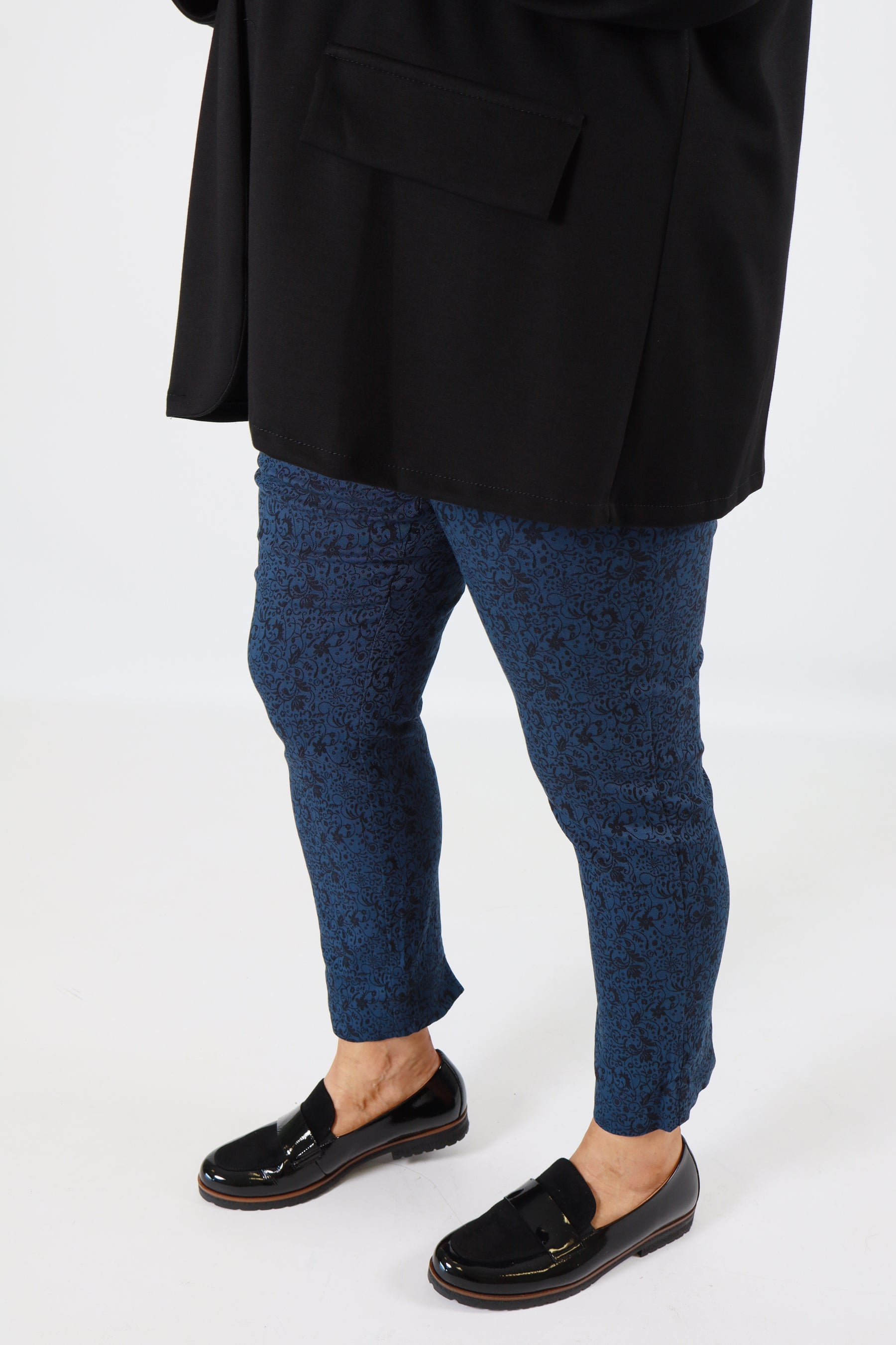 Person wearing black shoes, blue patterned socks, and a black suit on a white background