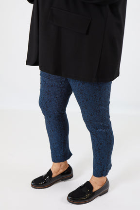 Person wearing black shoes, blue patterned socks, and a black suit on a white background