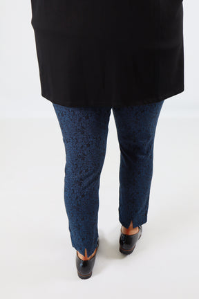 Person wearing black shoes, blue pants, and a black jacket on a white background