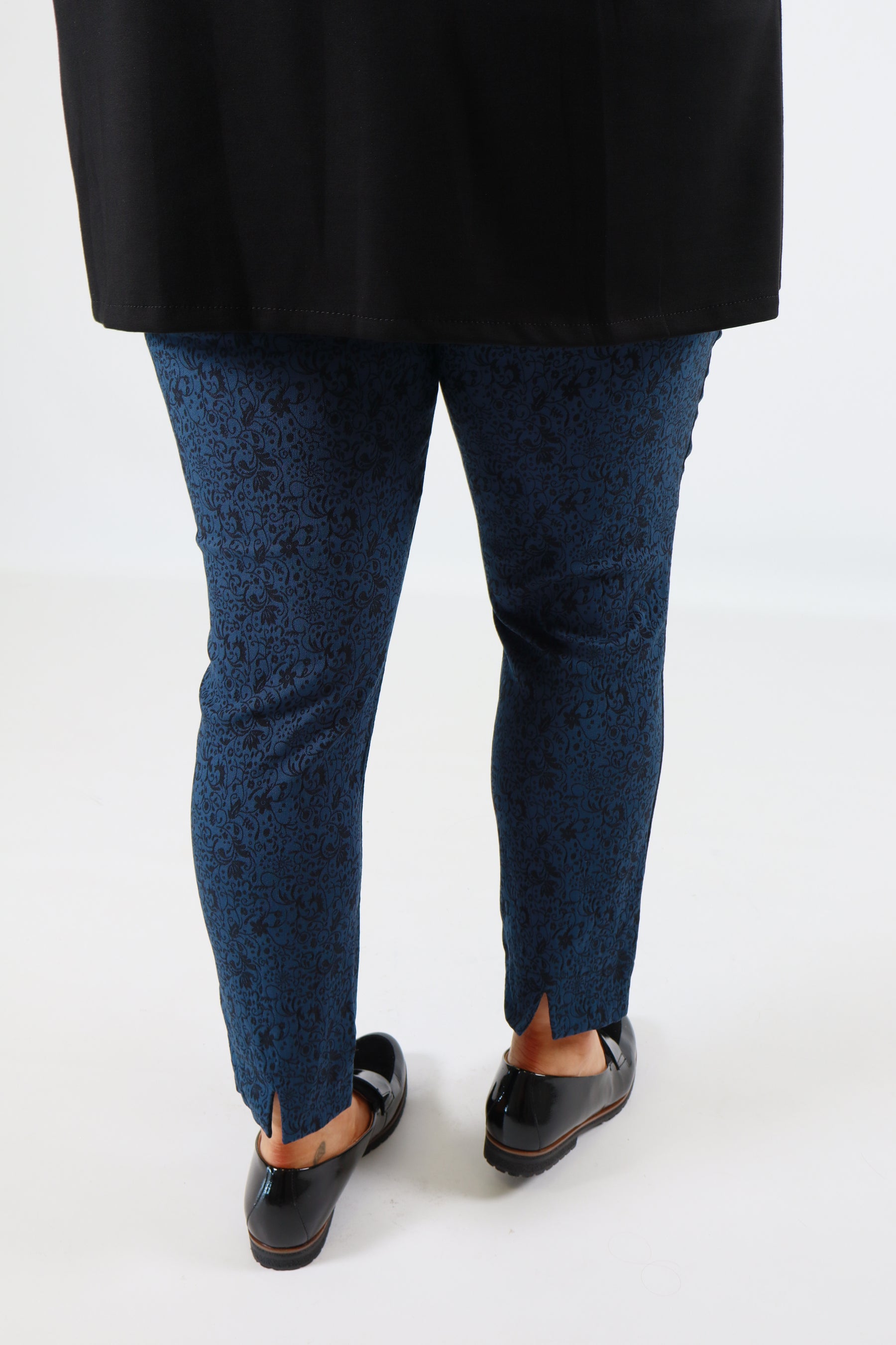 Person wearing blue pants and black shoes on a white background