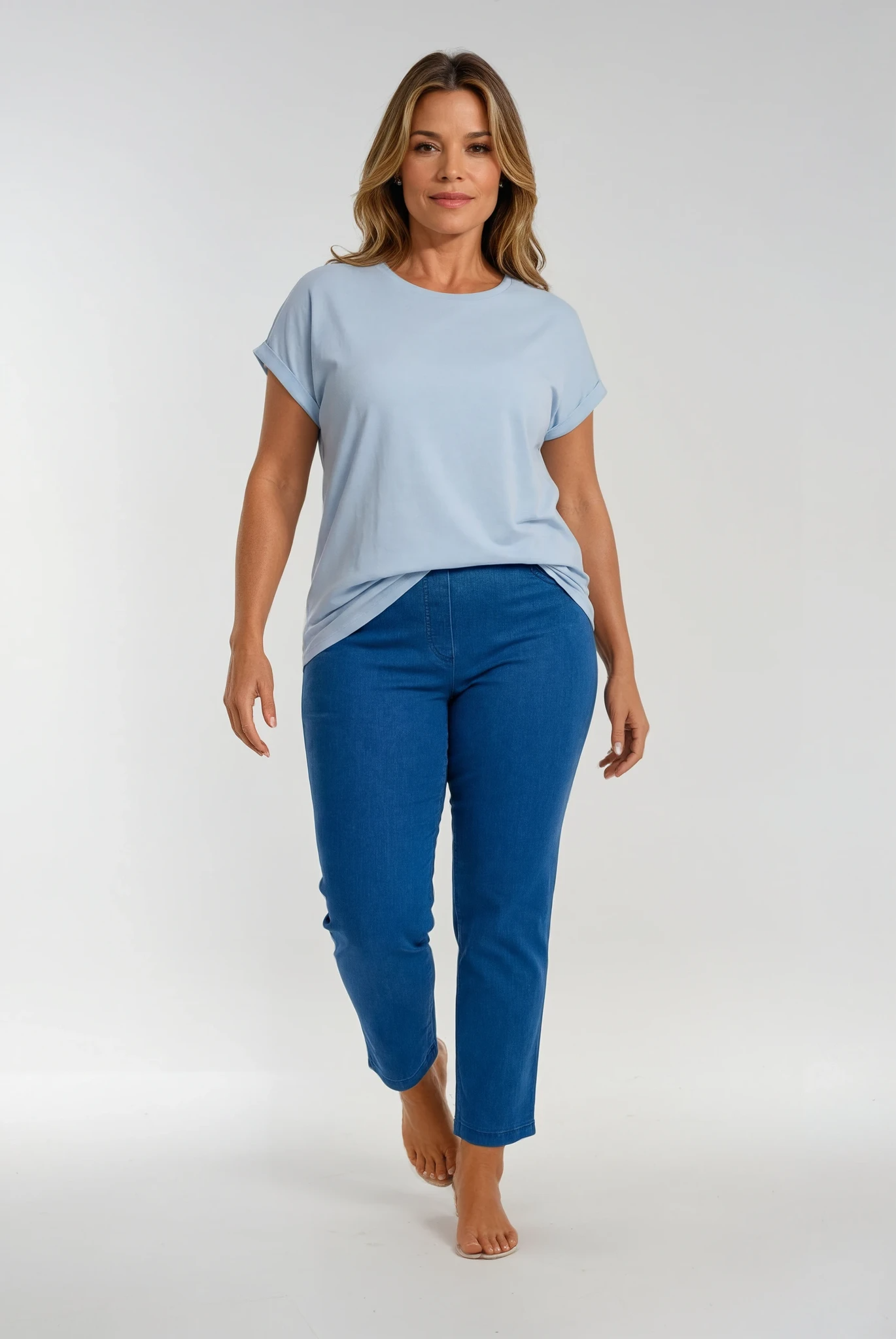 Woman wearing a light blue t-shirt and blue jeans on a white background