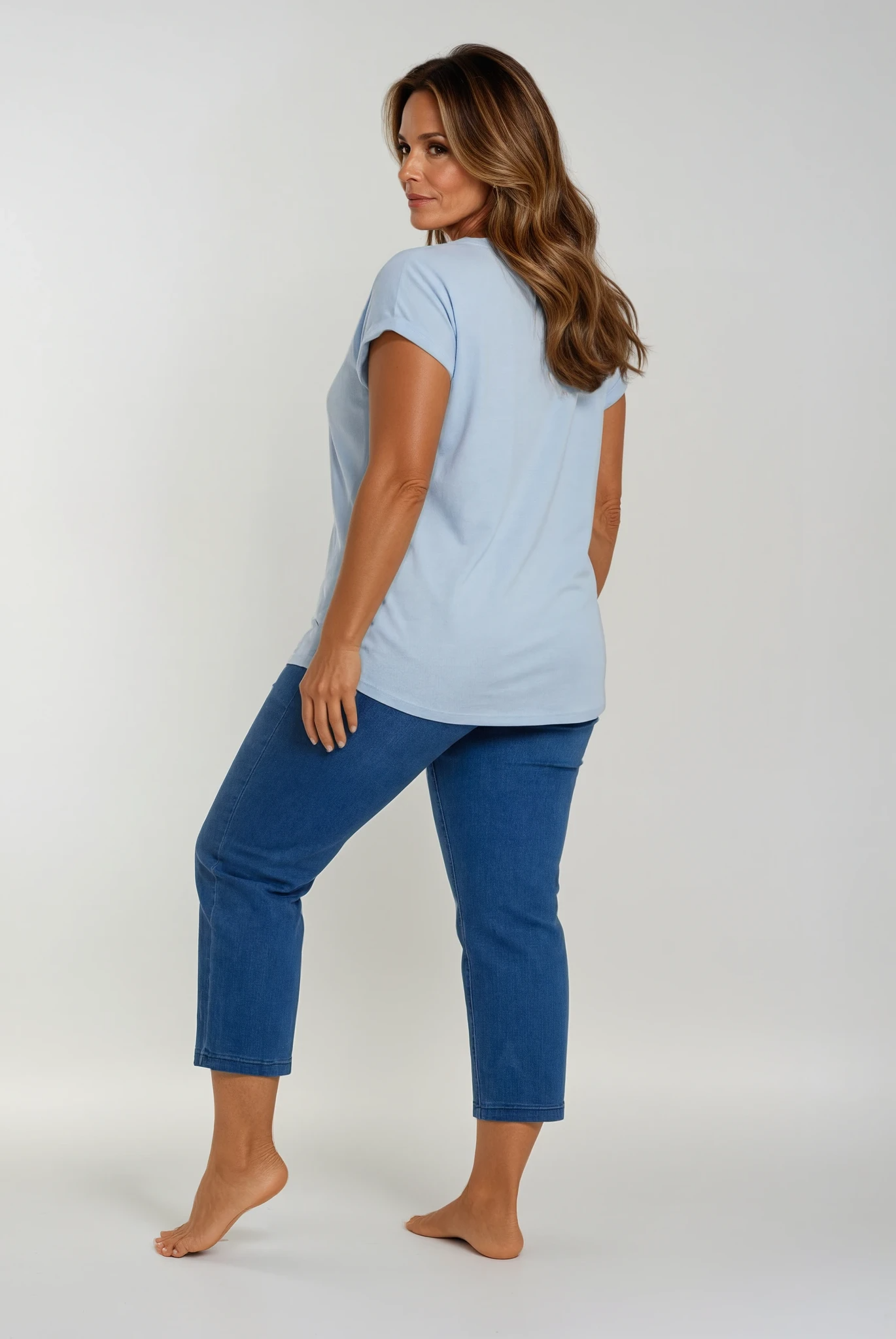 Woman wearing a light blue t-shirt and blue jeans on a white background