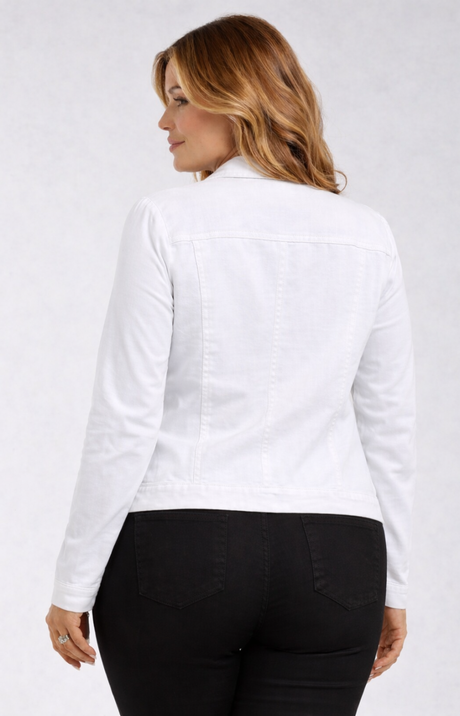 Woman wearing a white jacket and black trousers on a plain background