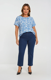 Woman wearing a blue patterned top and dark blue jeans on a white background