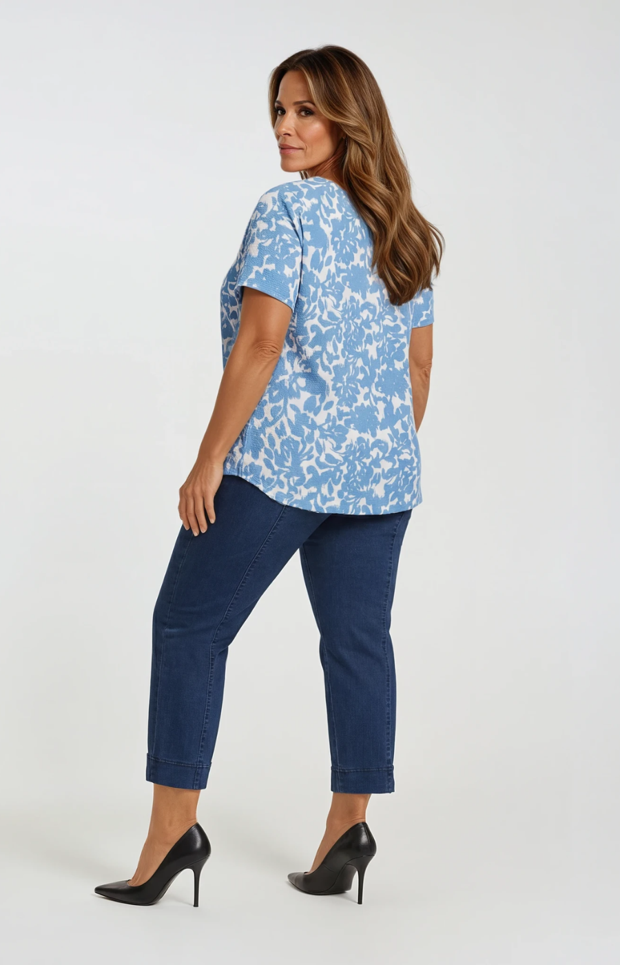 Woman wearing a blue floral blouse and navy pants on a white background