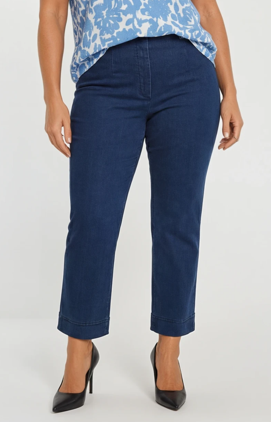 Person wearing blue pants and a patterned top on a white background