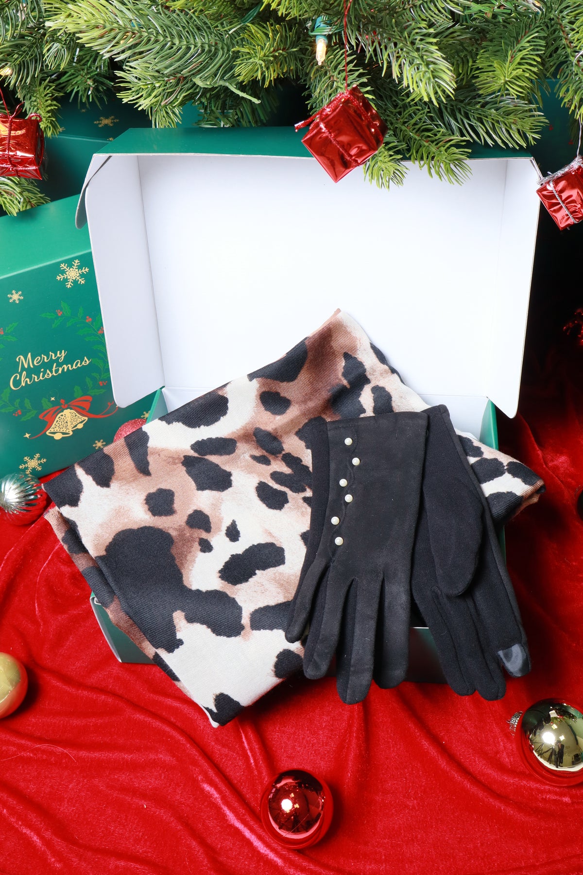 Pair of black gloves with leopard print pattern on a red fabric background with Christmas decorations.