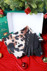 Pair of black gloves with leopard print pattern on a red fabric background with Christmas decorations.