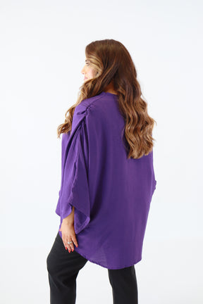 Person wearing a purple shirt and black pants on a white background