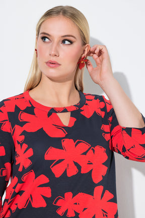 Woman wearing the Ulla Popken Floral Keyhole Top in Red, a navy top with red floral patterns, a round neckline with a keyhole cut out and 3/4 length sleeves against a white background