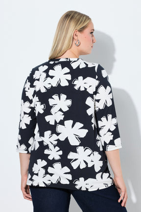 Woman wearing the Ulla Popken Floral Keyhole Top in White, a navy blue top with white floral pattern, a round neckline with a keyhole cut out and 3/4 length sleeves on a plain background