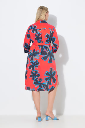 Woman wearing the Ulla Popken Floral Shirt Dress in Red, a red dress with blue floral pattern. This dress has a shirt collar, 3/4 length sleeves and a midi length, with a removable tie belt at the waist on a white background