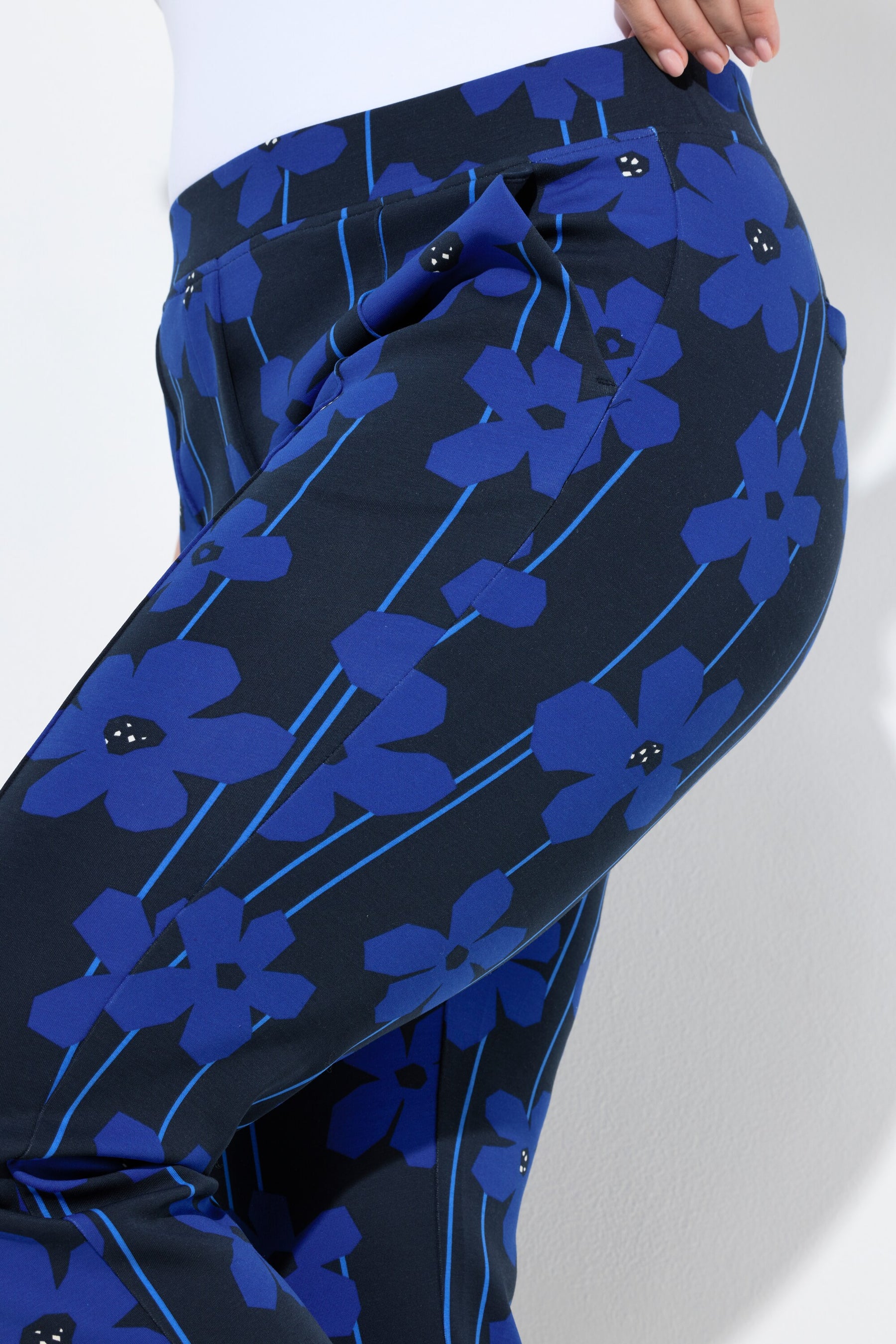 Women wearing the Ulla Popken Floral Trousers in Blue, a dark trousers with a blue floral design all over, showing a close up of the side pockets and floral design
