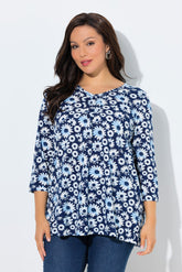 Woman wearing the Ulla Popken Flower Top in Blue, a blue floral patterned top with a V neckline with decorative pleats, 3/4 length sleeves and an A-line shape against a white background