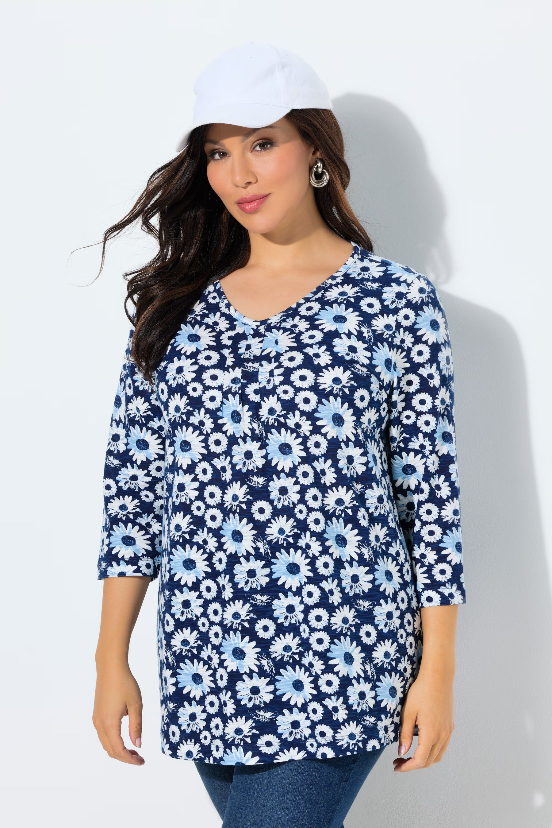 Woman wearing the Ulla Popken Flower Top in Blue, a blue floral patterned top with a V neckline with decorative pleats, 3/4 length sleeves and an A-line shape against a white background 