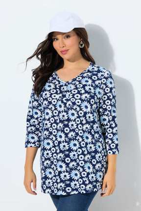 Woman wearing the Ulla Popken Flower Top in Blue, a blue floral patterned top with a V neckline with decorative pleats, 3/4 length sleeves and an A-line shape against a white background 