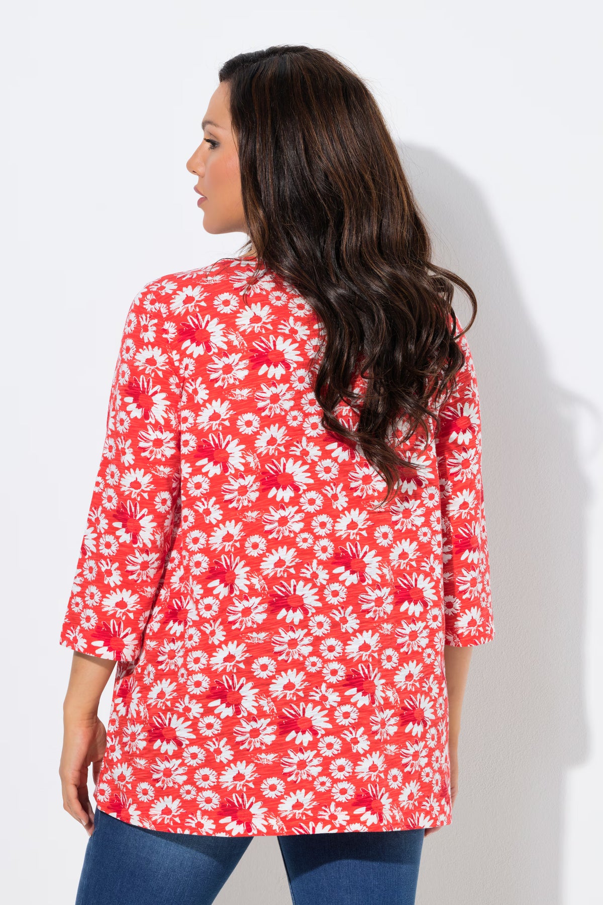 Woman wearing the Ulla Popken Flower Top in Red, a red floral top with a pleated V neckline, 3/4 length sleeves and an A-line shape against a white background