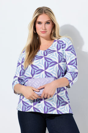Woman wearing the Ulla Popken Geometric Top in Purple, a purple geometric patterned top with a V neckline, 3/4 length sleeves and an A-line shape against a white background 