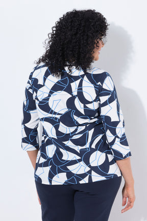A woman with curly black hair is shown from the back wearing the Ulla Popken Keyhole Leaf Print Blouse in Navy, a navy blue, white, and light blue abstract patterned blouse with three-quarter sleeves, paired with navy pants, against a plain white background.