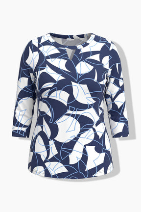 A ghost image of the Ulla Popken Keyhole Leaf Print Blouse in Navy, A women's three-quarter sleeve top with a modern abstract geometric pattern in navy blue, white, and light blue, shown on a light gray background.