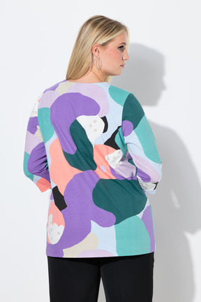 Woman wearing the Ulla Popken Multicolor A-Line Top, a colorful abstract patterned top with a tunic neckline, 3/4 length sleeves and an A-line shape against a white background