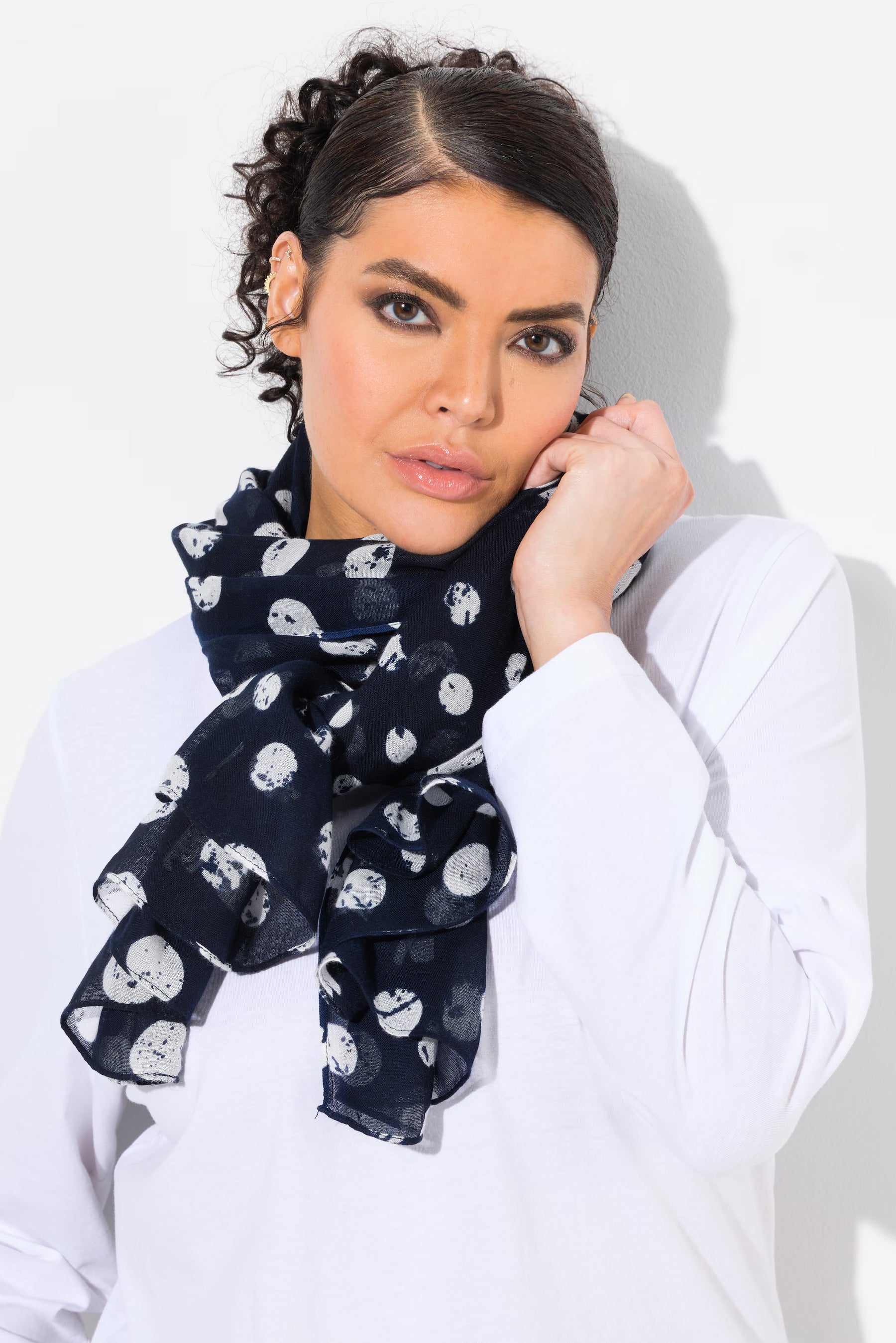 Woman wearing a navy blue scarf with white patterns on a white background