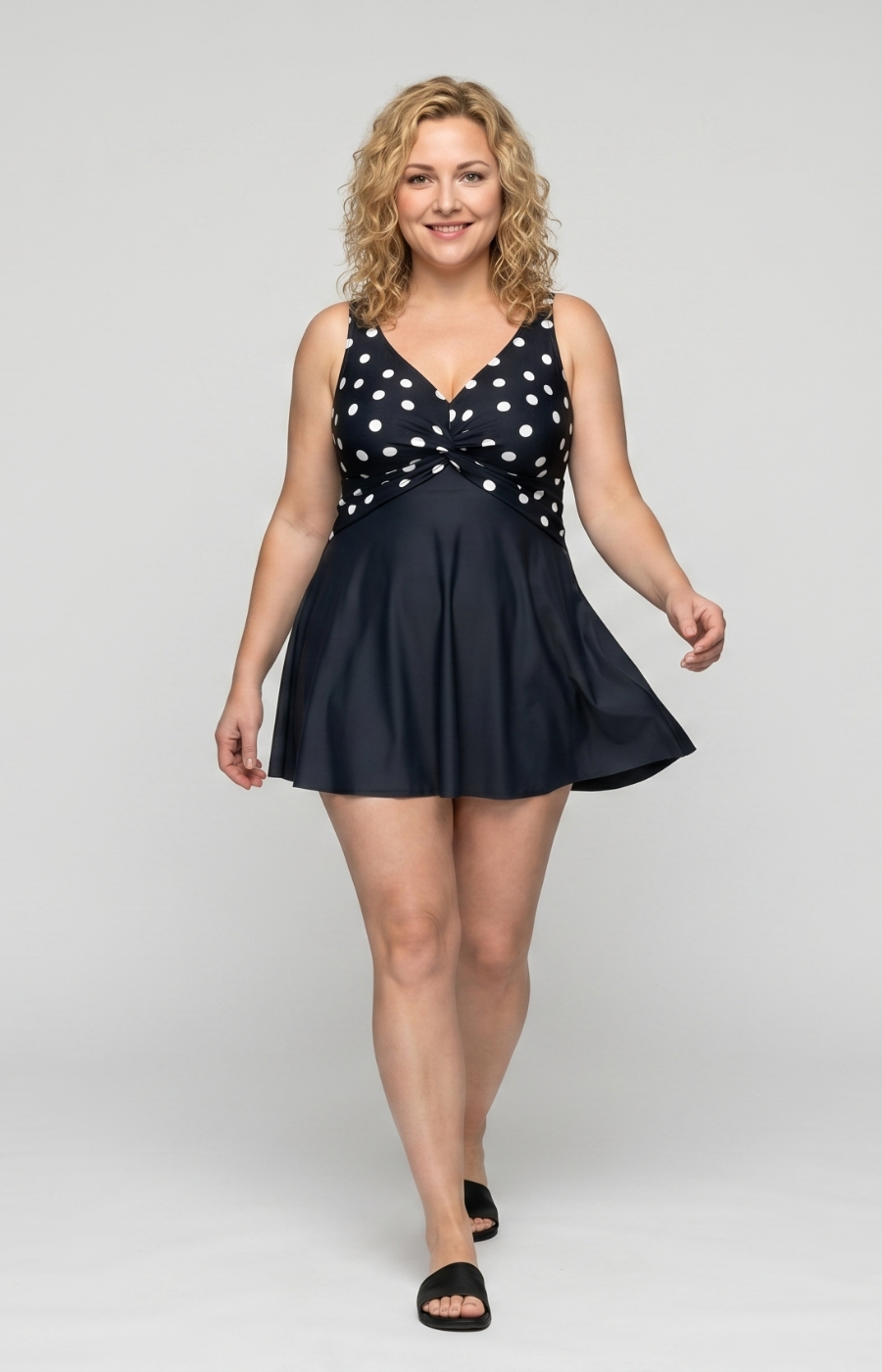 Woman wearing a navy swimsuit with white polka dots on a white background
