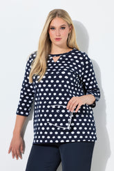 Woman wearing the Ulla Popken Polka Dot Keyhole Top in Navy, a navy blue top with white polka dots against a light background