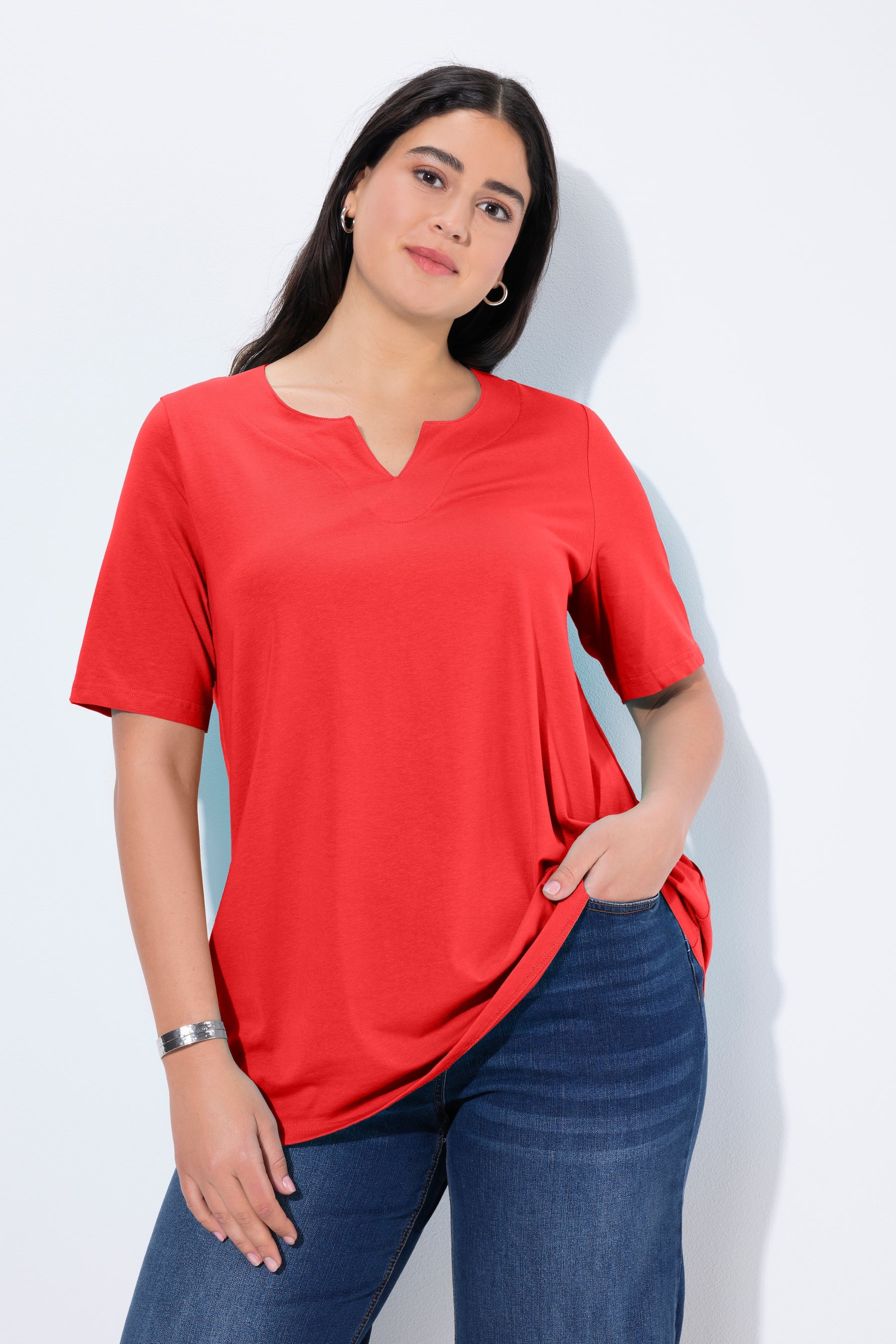 women wearing the Ulla Popken Tunic Neck T-Shirt in Red, an A-line T-shirt with short sleeves and a tuning neckline, worn with blue jeans
