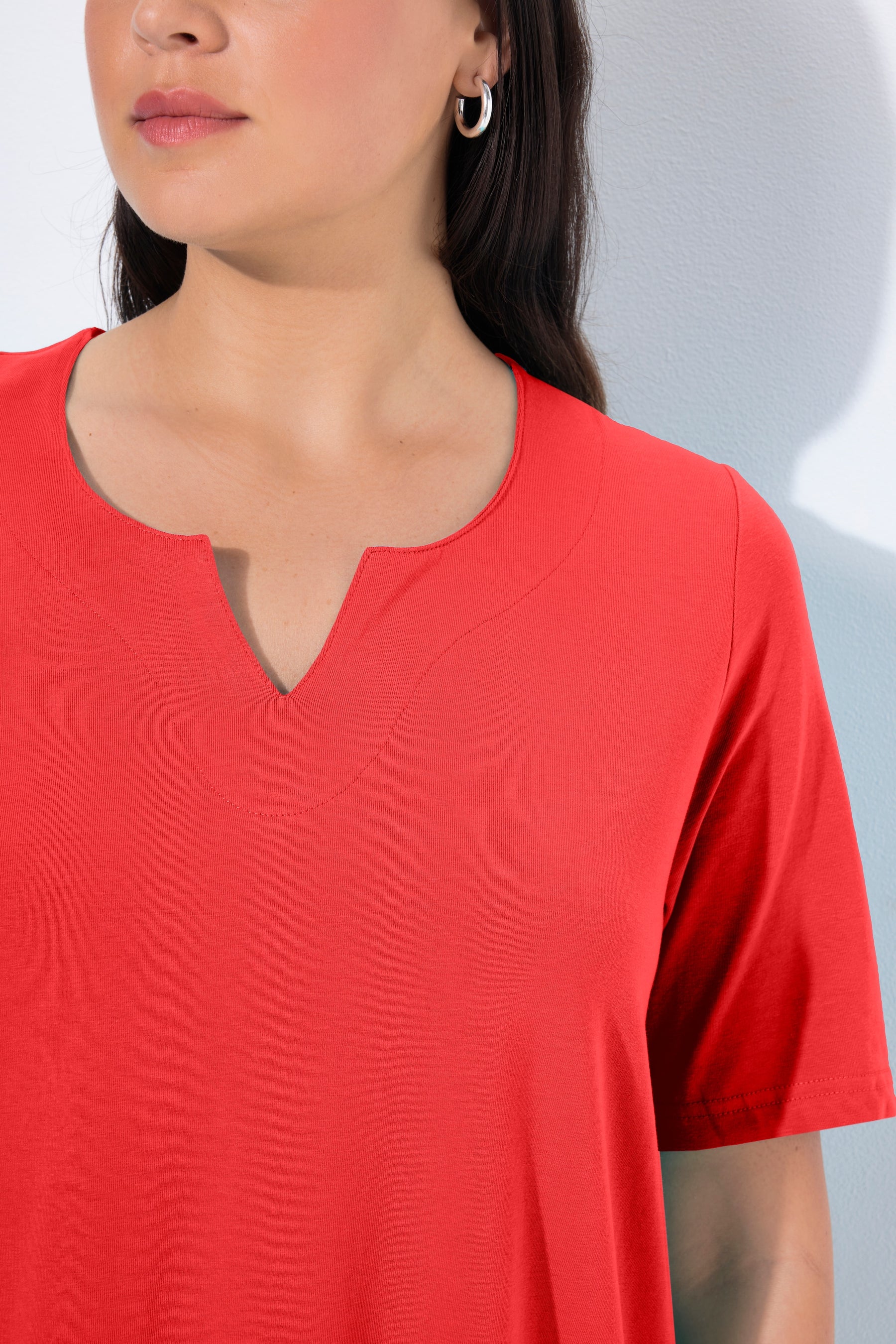 Close-up of a women wearing the Ulla Popken Tunic Neck T-Shirt in Red, a red shirt with a tunic neckline with short sleeves in a vibrant red shade