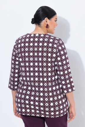A woman modeling the Ulla Popken Wine Print Blouse, a three-quarter sleeve top with a dark purple and white geometric diamond pattern, paired with matching dark purple pants, against a light gray studio background.