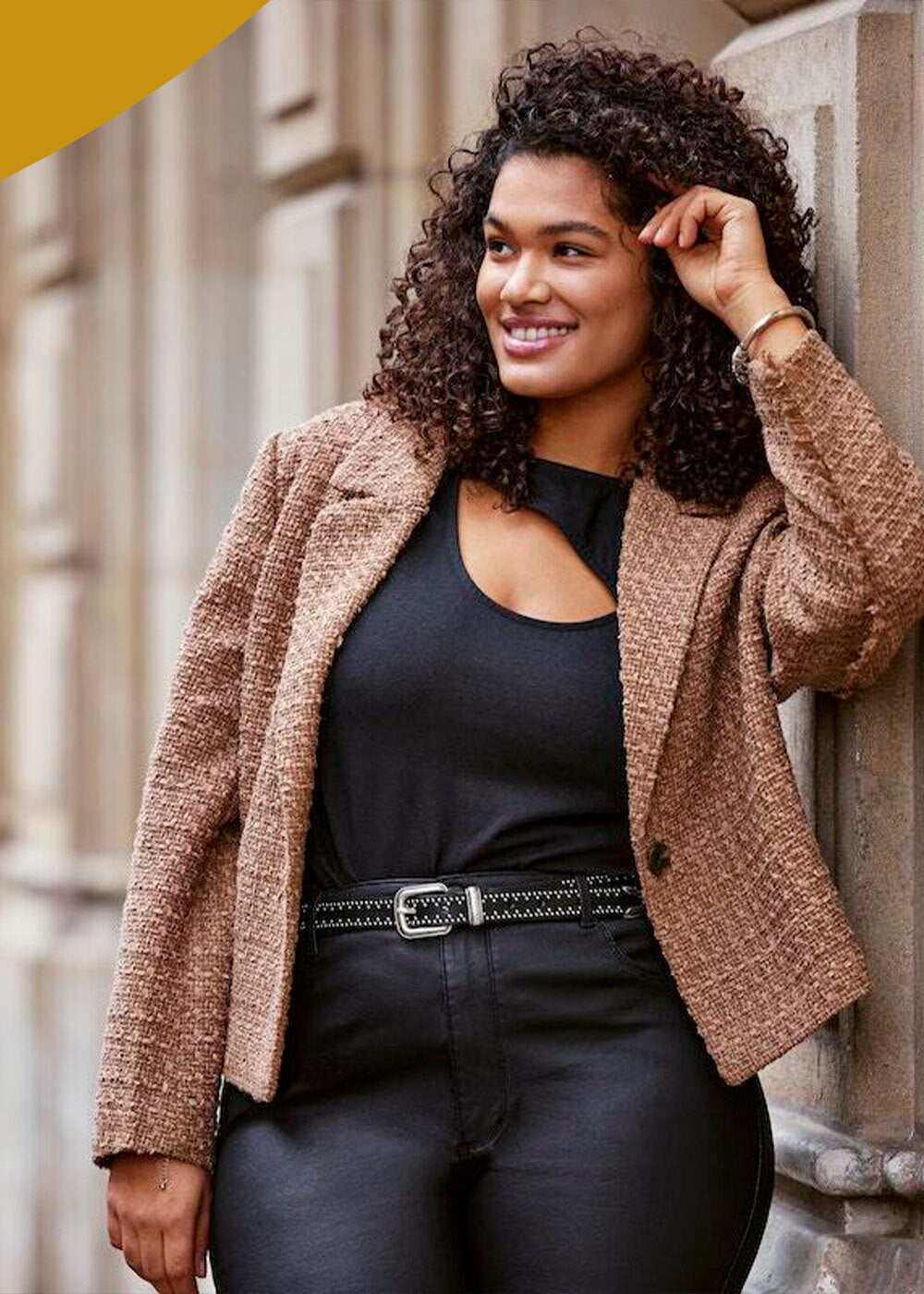 A woman wearing a black top and a brown blazer